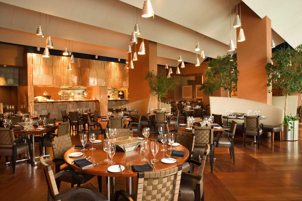 Scatto di una trattoria tipica nel borgo antico di Gaeta, con tavoli rustici all’aperto, clienti che mangiano tielle e piatti di pesce, scorcio di vicolo e insegne tradizionali