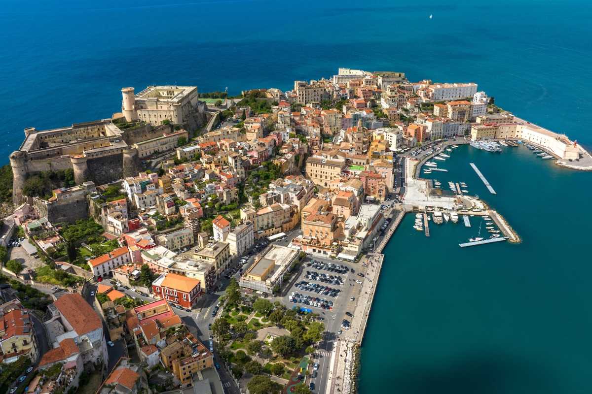 Scorcio ravvicinato di una caletta appartata a Gaeta, acqua trasparente, scogli bianchi, pochi bagnanti e vegetazione mediterranea